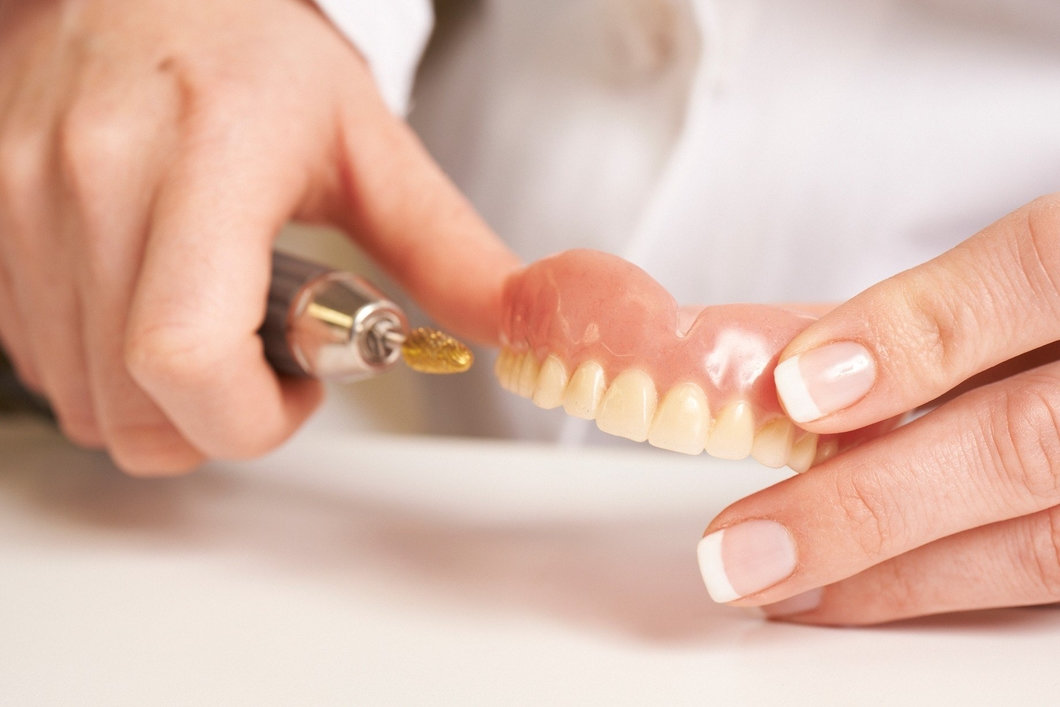 Зубной техник проводит перебазировку съемного протеза
